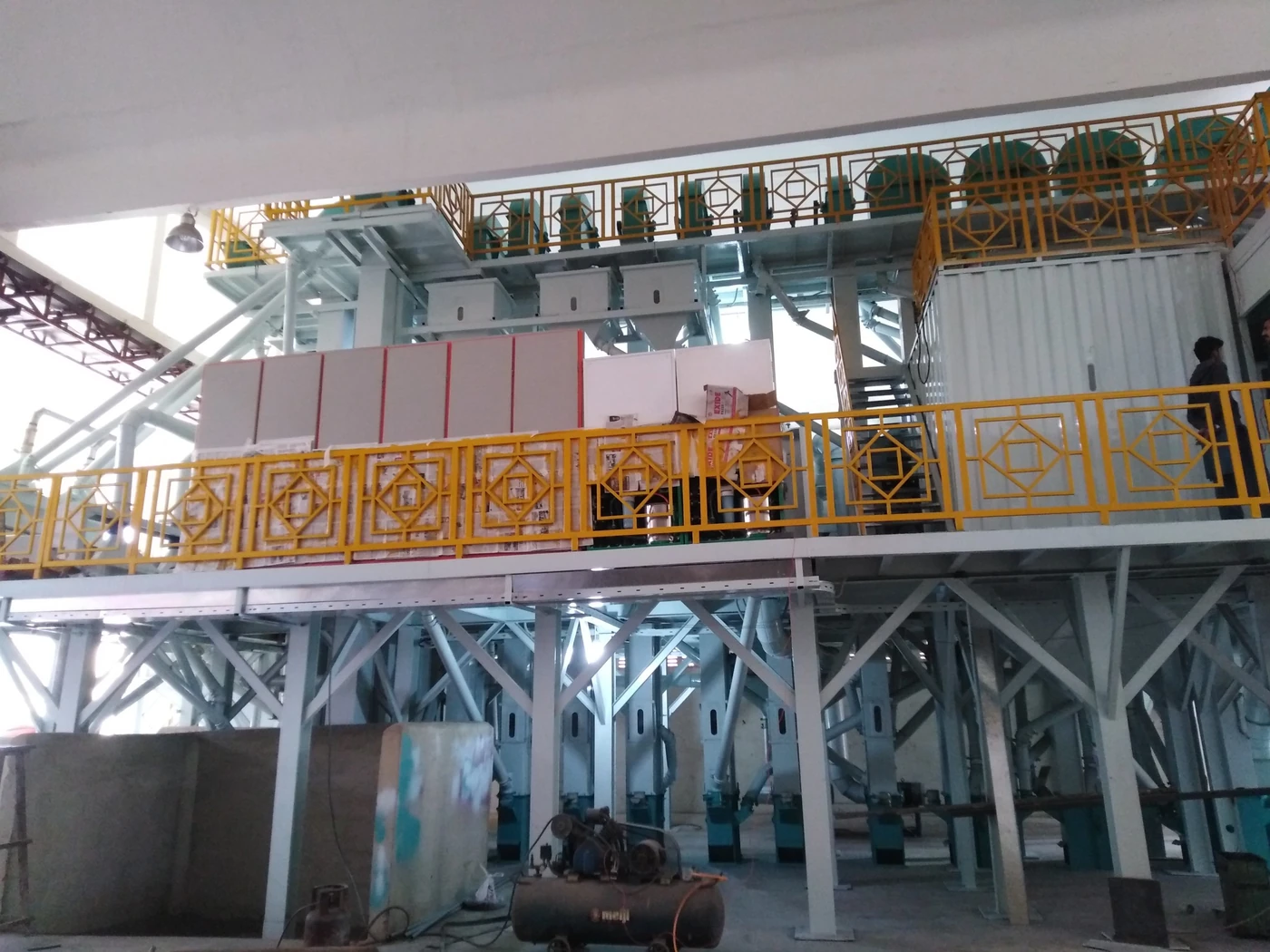 Fabricated steel platform and frame structure with yellow railings inside a rice mill